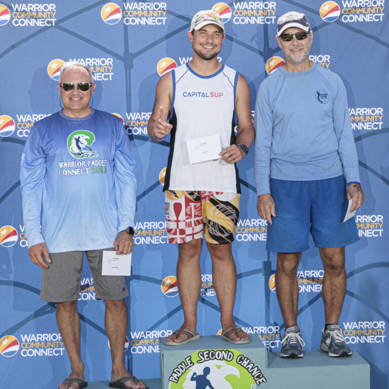 three men standing on a podium with one holding a medal