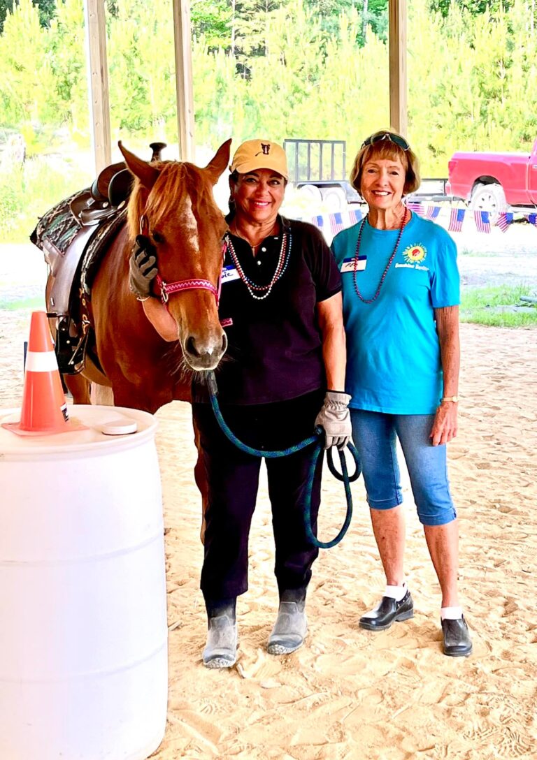 two women are standing next to a horse