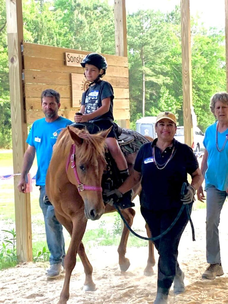 a woman walking a horse with a boy on it