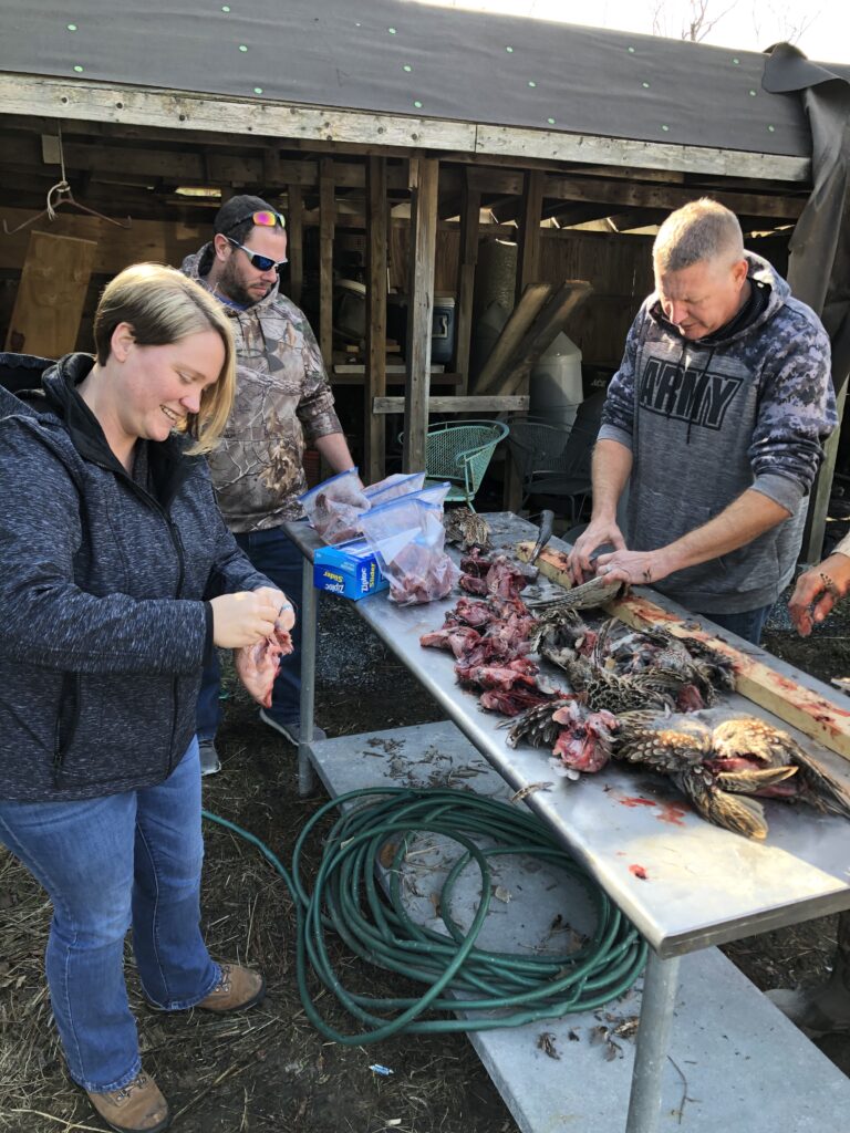three people standing around a table with food on it