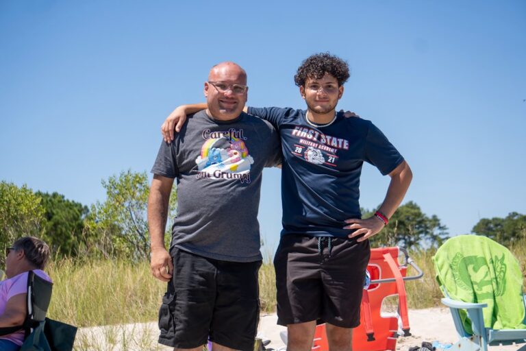 two men standing next to each other on a beach