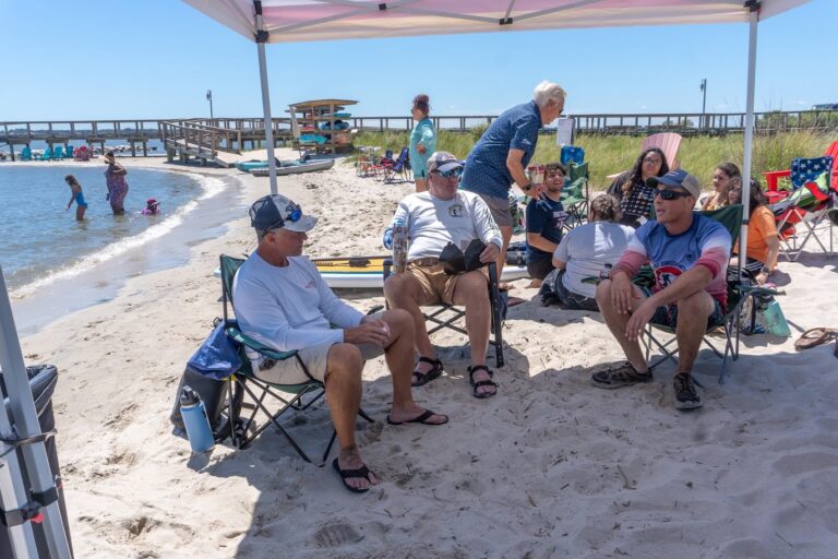 a group of people sitting on top of a sandy beach