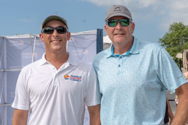 two men standing next to each other in front of a tent
