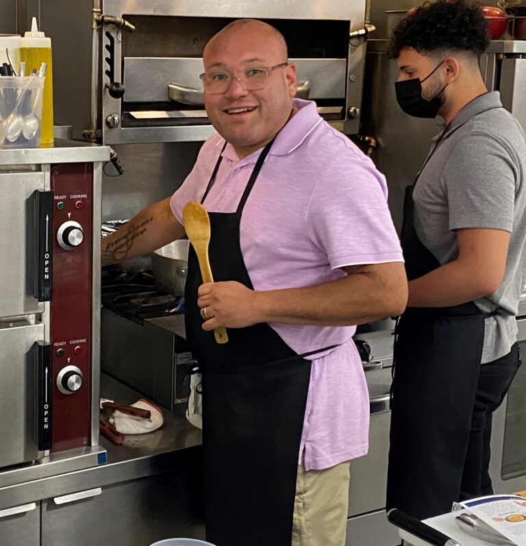 two men in a kitchen preparing food with spatulas