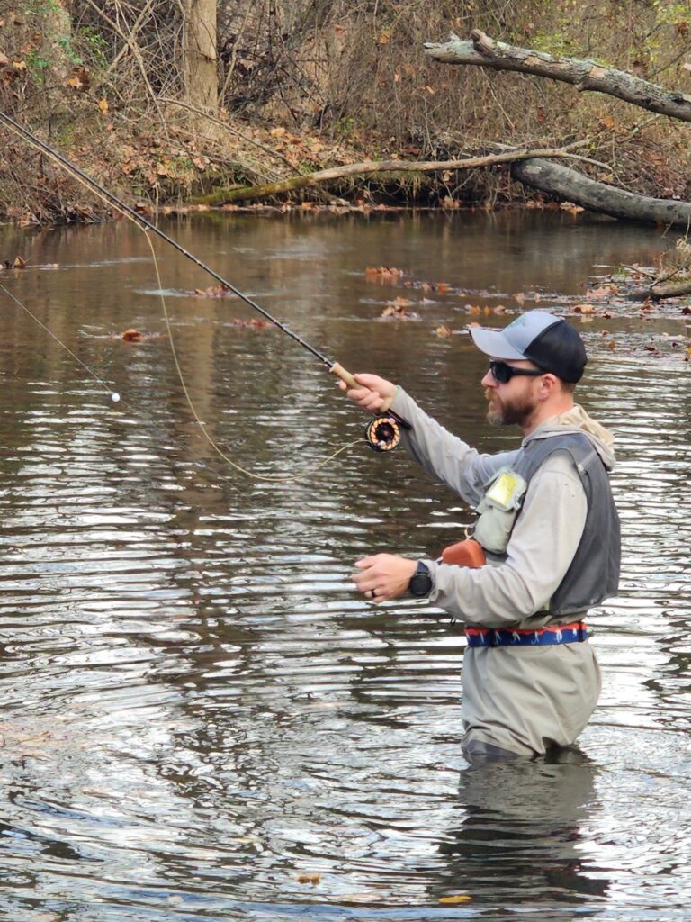 a man standing in the water while holding a fishing rod