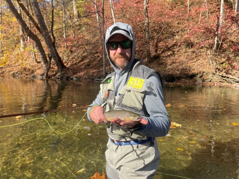 a man holding a fish while standing in the water