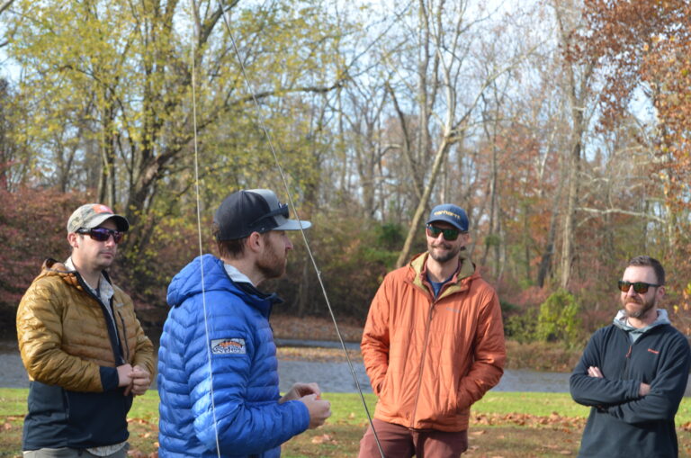 four men standing in a park with trees in the background