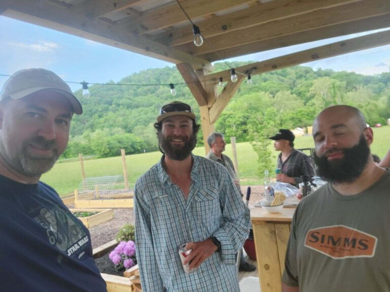 three men are standing under a wooden structure