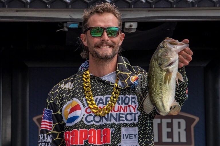 a man holding a fish while wearing sunglasses
