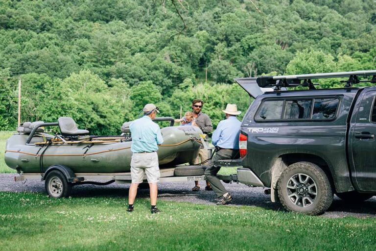 three men loading a boat onto a truck