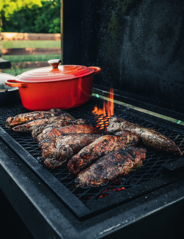 a grill with some meat and a pot on it