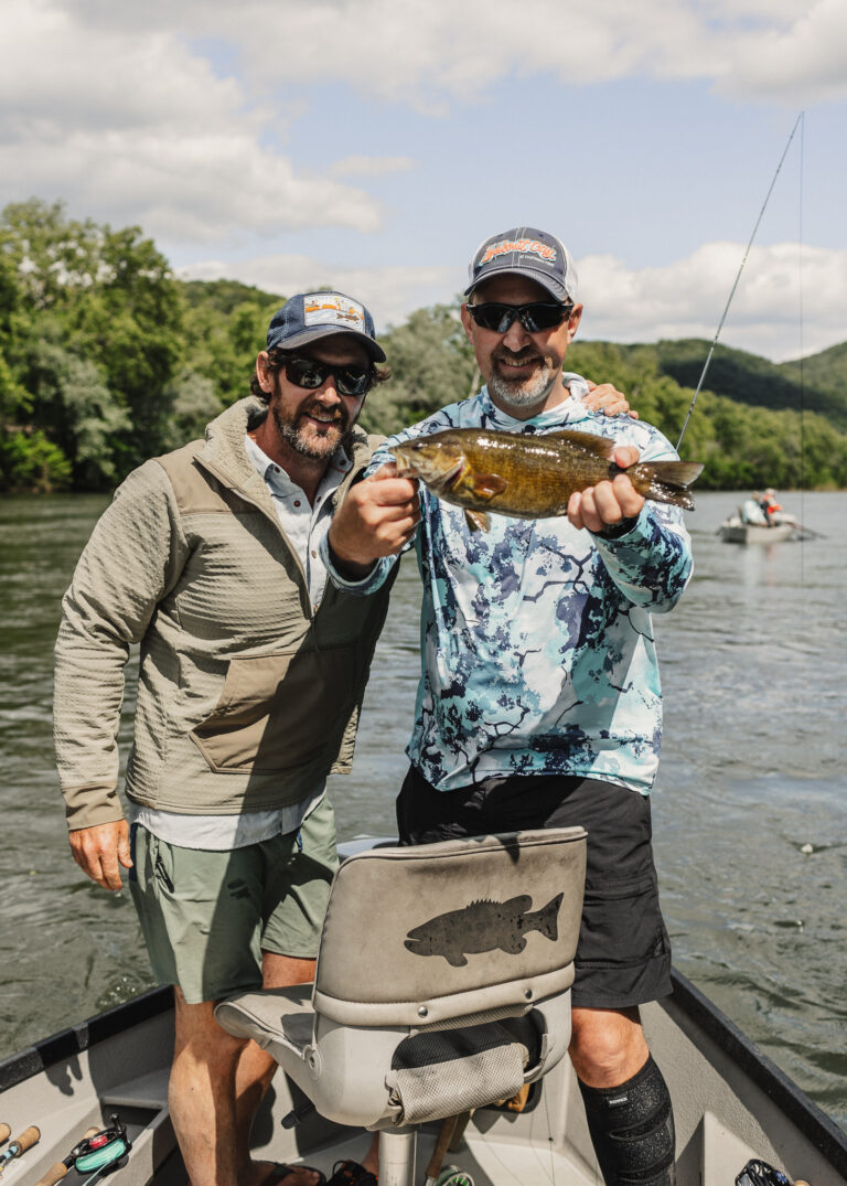 two men on a boat holding a fish