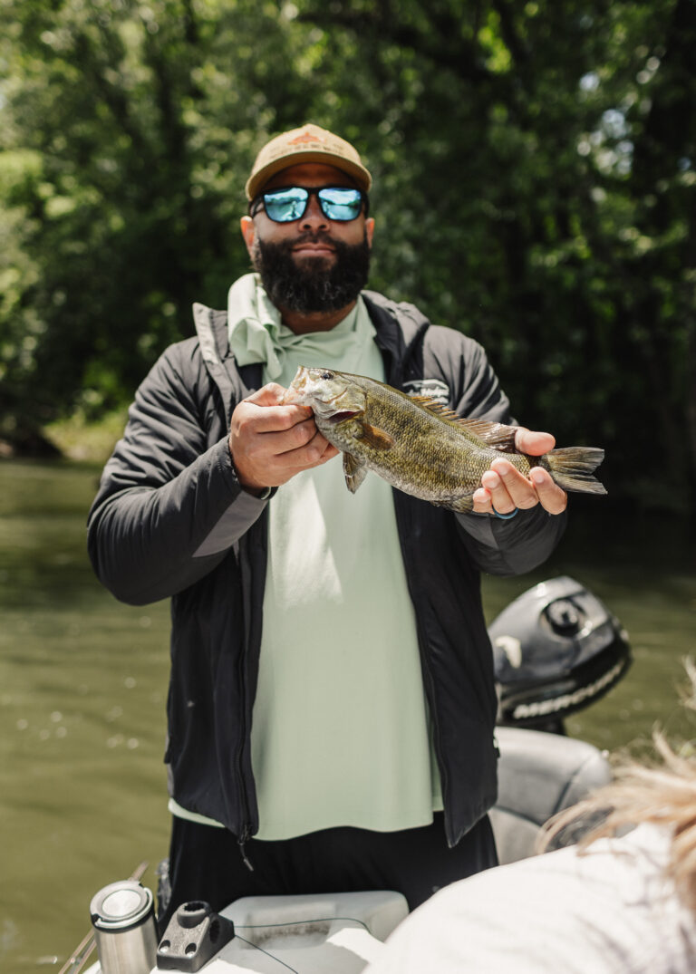 a man holding a fish while standing on a boat
