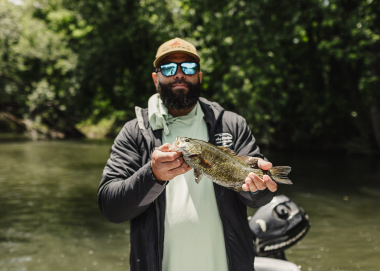 a man holding a fish while standing on a boat