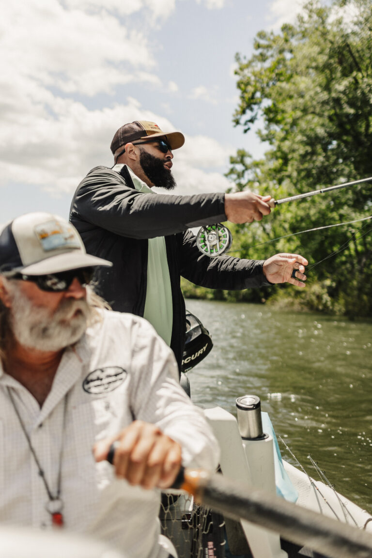two men on a boat fishing on a river