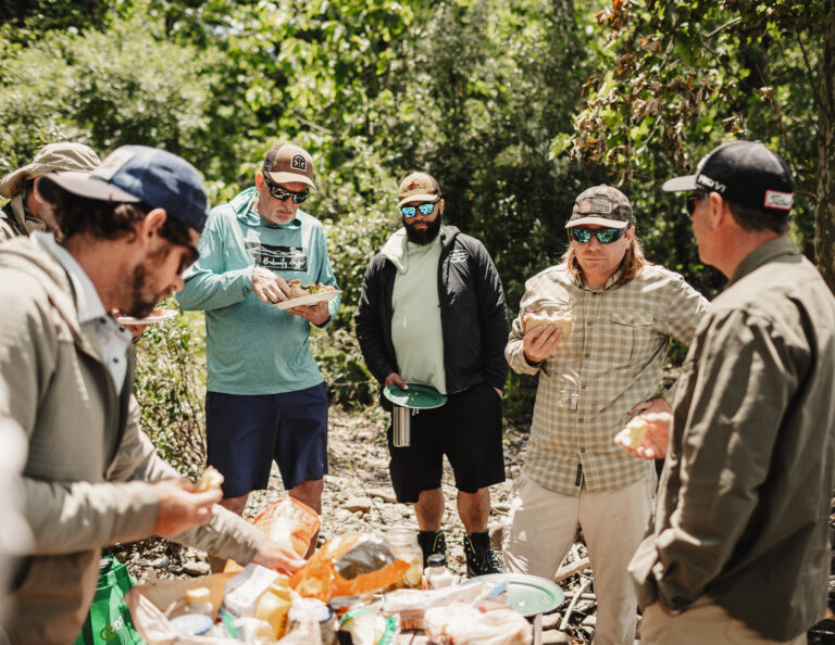 a group of men standing around a table filled with food