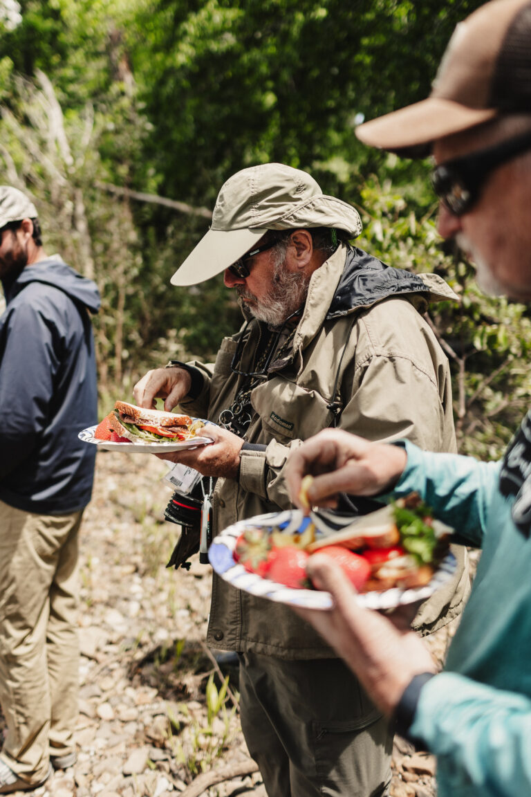 a group of men standing around each other eating food