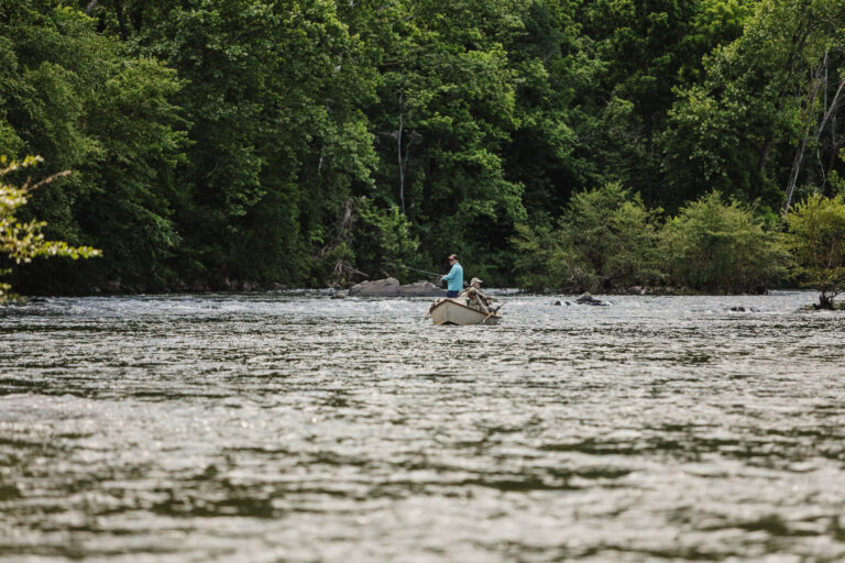 a person on a small boat in the middle of a river