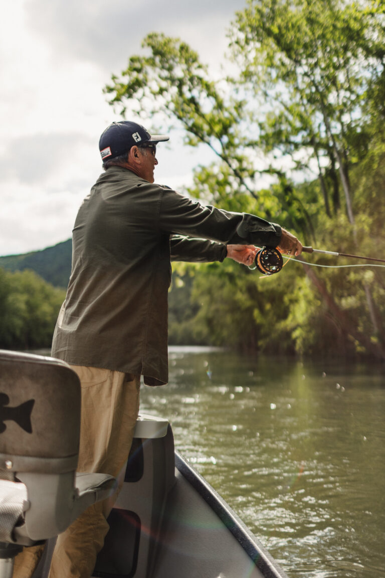 a man fishing on a boat on a river