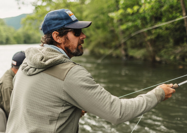 a man holding a fishing rod while standing on a boat