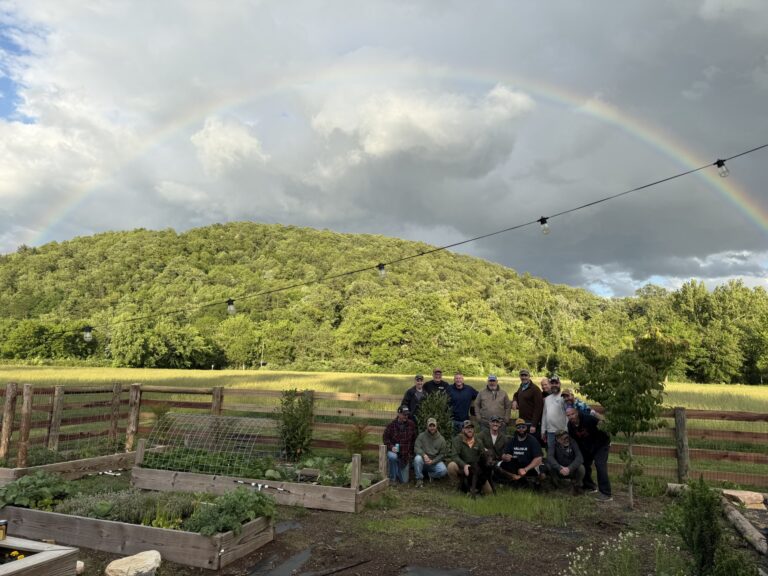 a group of people standing in a field under a rainbow