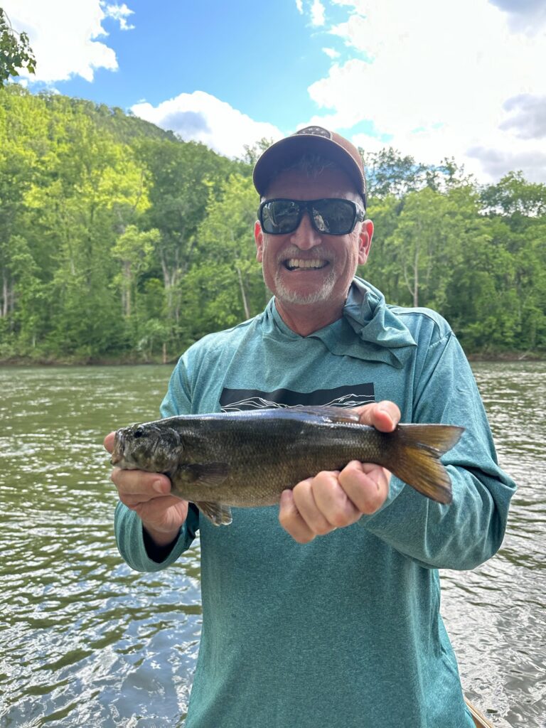 a man holding a fish while standing on a boat