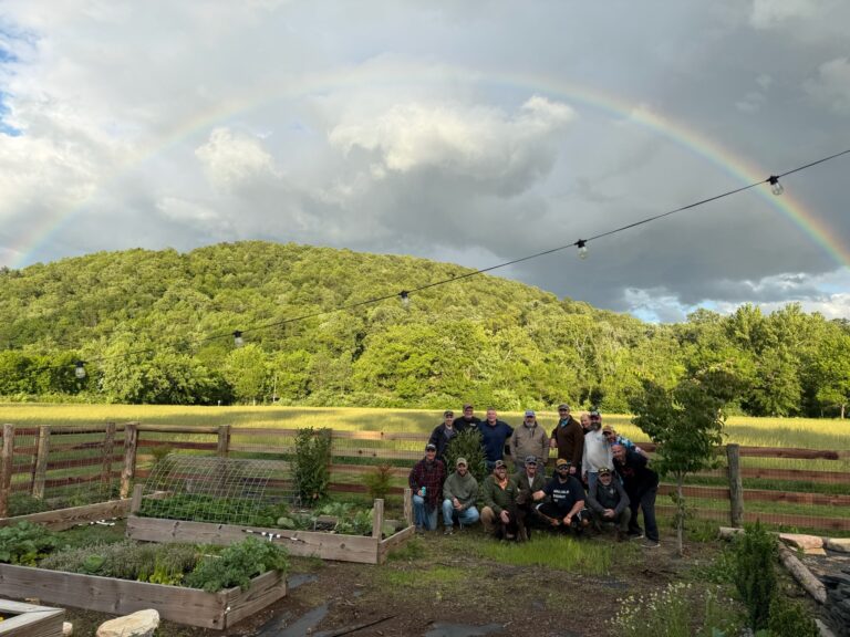 a group of people standing in a field under a rainbow