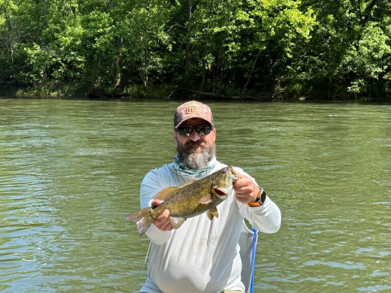 a man holding a fish while standing in the water