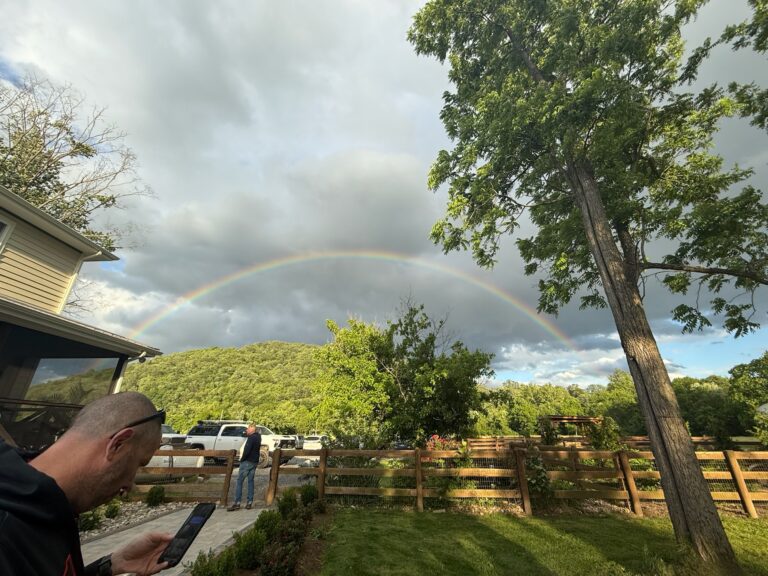 a man is taking a picture of a rainbow