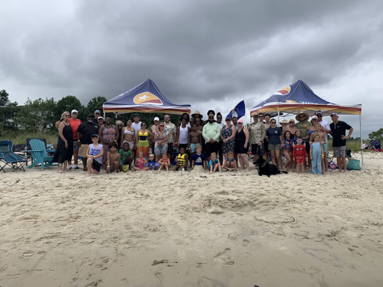 a group of people standing on top of a sandy beach