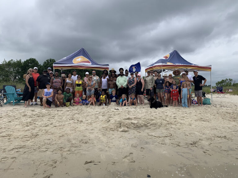 a group of people standing on top of a sandy beach