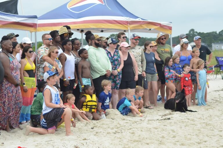 a group of people standing on top of a sandy beach