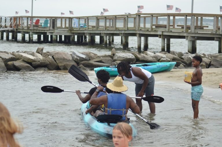 a group of people on a beach with kayaks