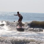boy practicing to surf on a wave with arms out to side
