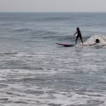 Instructor helping young boy surf a wave