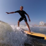 boy surfing with the beach and hotels in the background