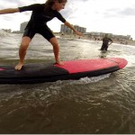 Guy taking a picture of girl surfing a wave
