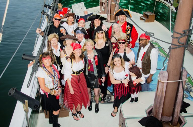 group of people dressed in festive pirate gear on deck of ship