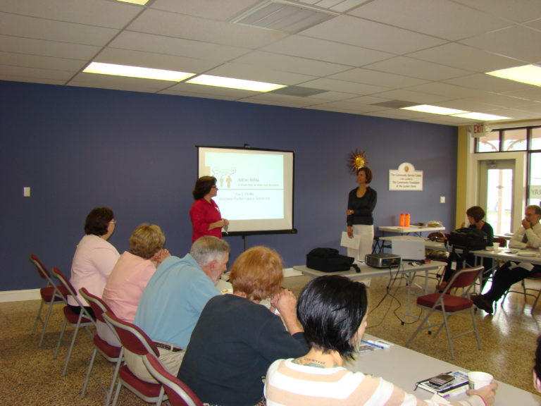 presentation with projector and screen given to group of adults sitting at folding tables