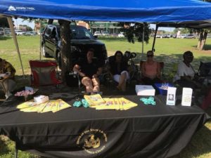 Staff members seated behind outdoor booth table