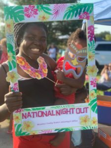 Girl holding baby posing with cutout frame with tropical theme