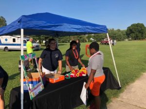 Two staff members interact with boy at National Night Out booth