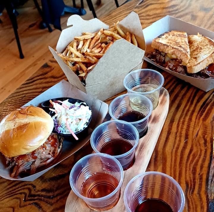 sandwiches, fries, and wine on a wood table