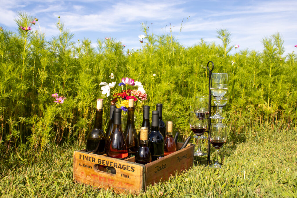 Case of wine next to multiple glasses in the field of flowers