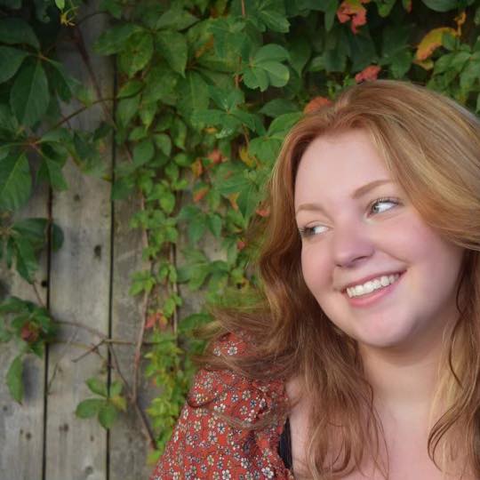 Headshot of a young girl with strawberry blonde hair and floral print shirt